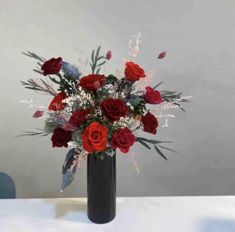 1) 照片顯示一束紅玫瑰,放在黑色花瓶中,背景是白色牆壁