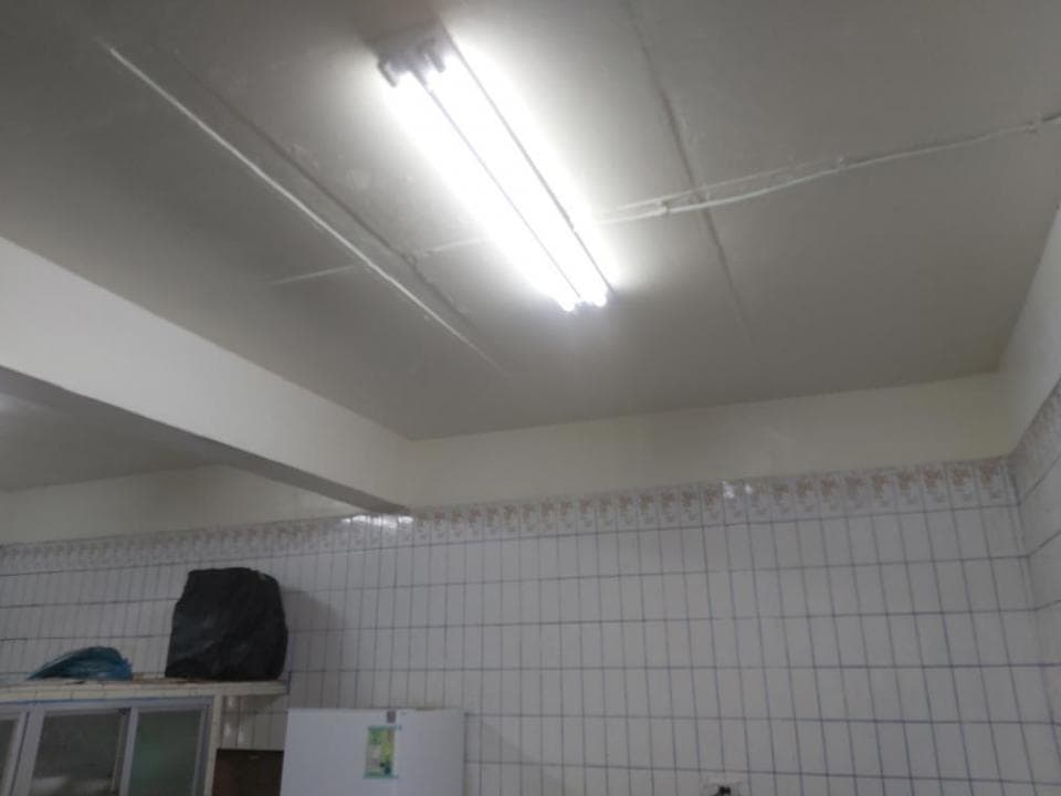 1) 照片顯示一個白色天花板上的螢光燈管,房間的牆壁為白色瓷磚,房間裡有一台冰箱