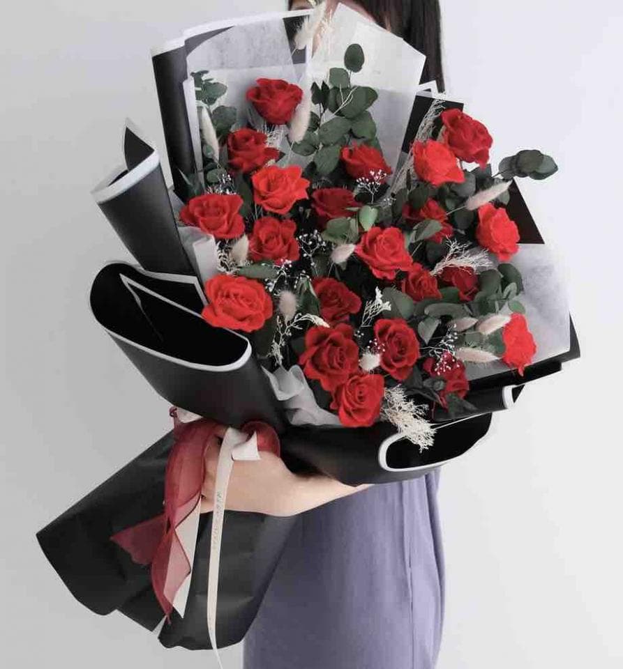 這張照片是一束用黑色包裝紙包裹的紅玫瑰花束。