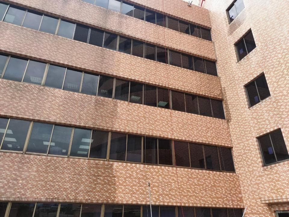 1) 照片顯示一座外牆為紅磚的建築物,建築物有多層,每層都有多扇窗戶,窗戶上看起來好像有些灰塵