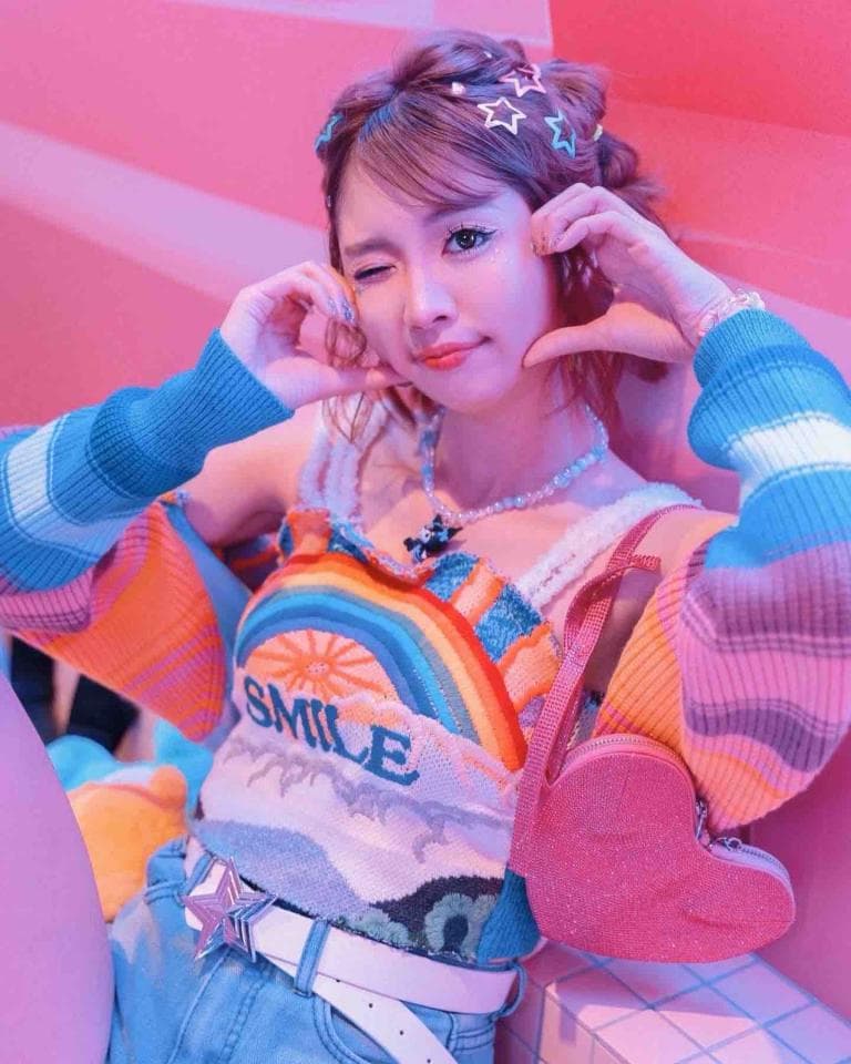 這張照片是一個年輕女孩,她戴著星星髮飾,穿著彩虹色的毛衣和牛仔褲,看起來很可愛。