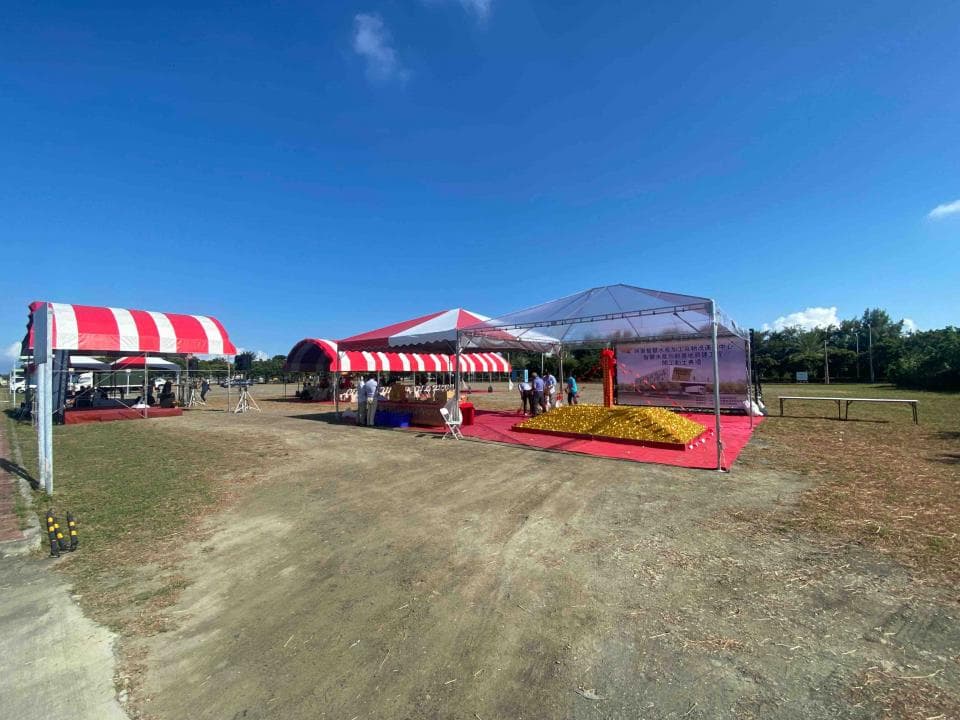 這張「戶外活動」的照片是 一個有三個紅色和白色條紋的帳篷,地上放了一些金色的東西,還有許多人站在帳篷裡。