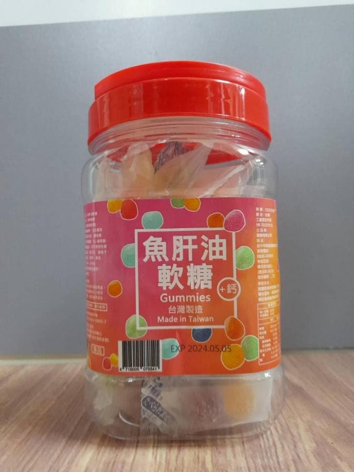 這張「魚肝油軟糖」的照片是一個裝滿彩色軟糖的透明罐子,罐子上印有產品名稱和製造商信息。罐子蓋子是紅色,上面印有產品名稱。
