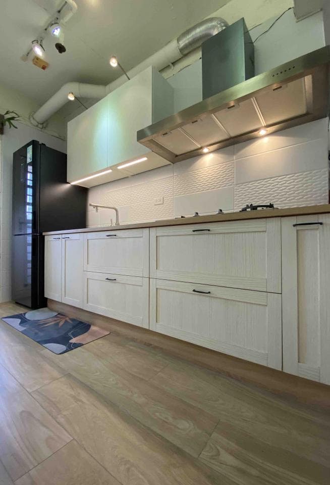 這張照片是一間現代化的廚房,最重要的是廚房的木紋櫥櫃。櫥櫃採用白色木紋,並配有黑色的拉手,整體風格簡潔大方,非常耐看。