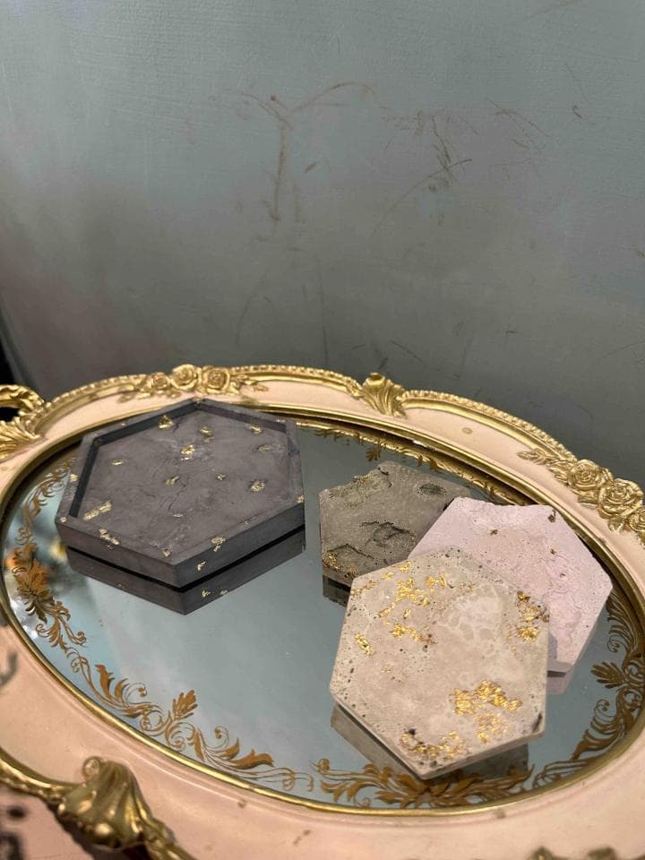 1. 照片顯示一個粉紅色和金色邊框的托盤,托盤上放著一個鏡子,鏡子裡有三個水泥製的六角形盤子