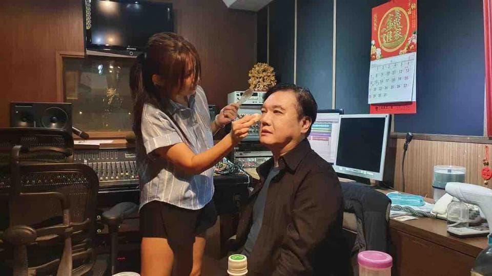 這張照片是一個工作室,照片中最重要的是一個男人正在接受化妝。