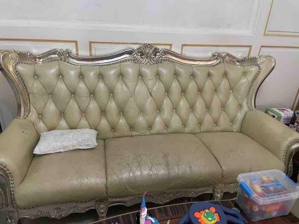 這張照片是一張帶有雕刻細節的古典沙發,上面有白色靠枕,看起來很舒適。