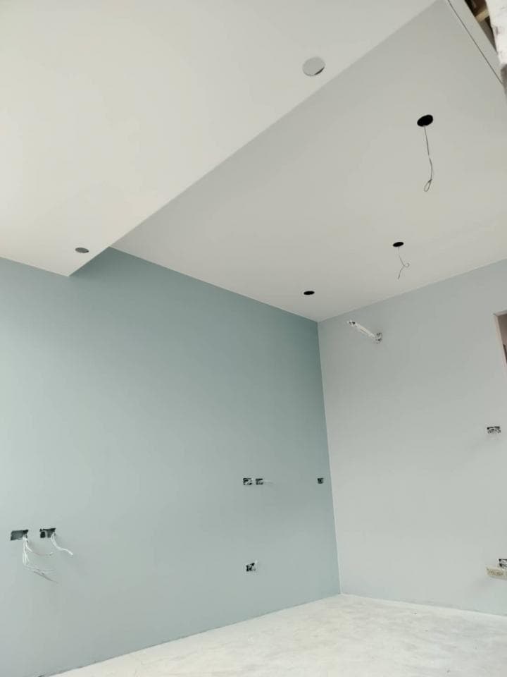 1) 照片顯示一個空的房間,牆壁是淺藍色,天花板是白色,房間裡的燈尚未安裝,房間地板是水泥地面