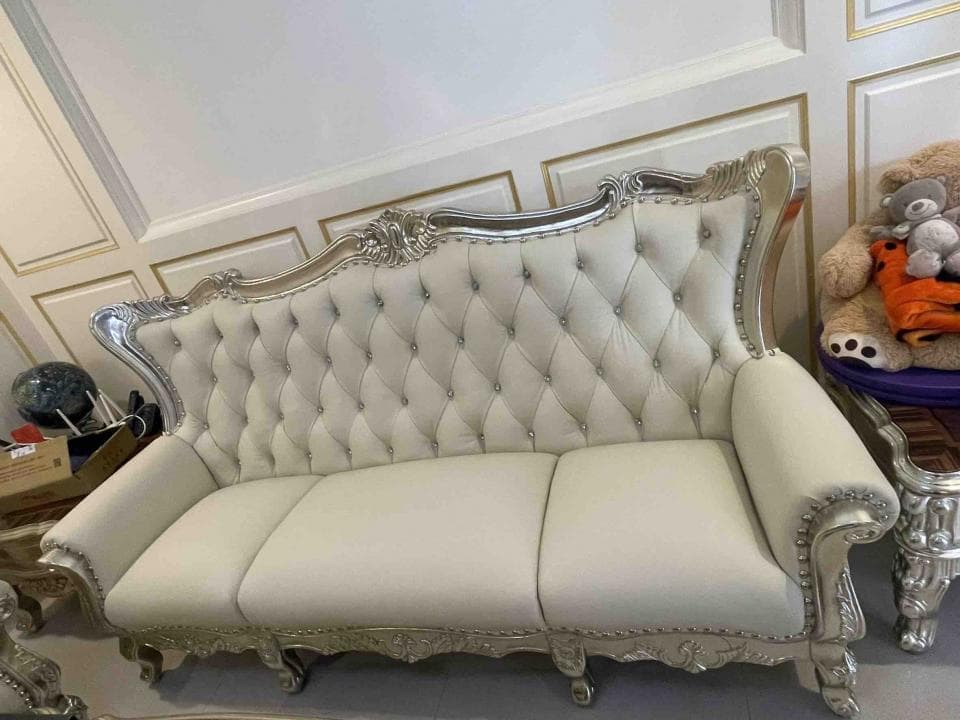 這張照片是一張白色復古風格的沙發,沙發的扶手和腿部都有精緻的雕刻,看起來非常奢華。