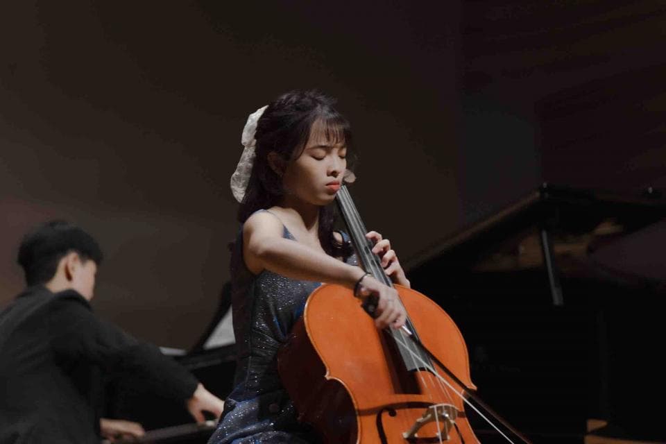 這張照片是一個年輕女孩正在演奏大提琴。她專注地看著琴絃,手指靈活地撥動琴絃,演奏出動聽的音樂。