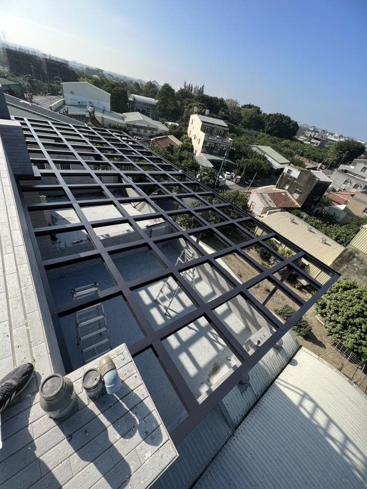 1) 照片顯示一座建築物屋頂上,裝設有黑色的金屬格柵結構, 格柵下方為透明的玻璃, 格柵結構覆蓋了大部分屋頂