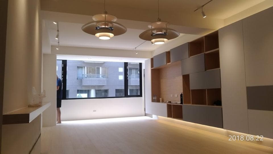 這張照片是一間現代化的客廳,以簡潔的設計為中心。牆上有一個大型的木質隔板,分成許多格,可以放置書籍、裝飾品或其他物品。隔板的設計巧妙,既美觀又實用,為客廳增添了一份時尚感。