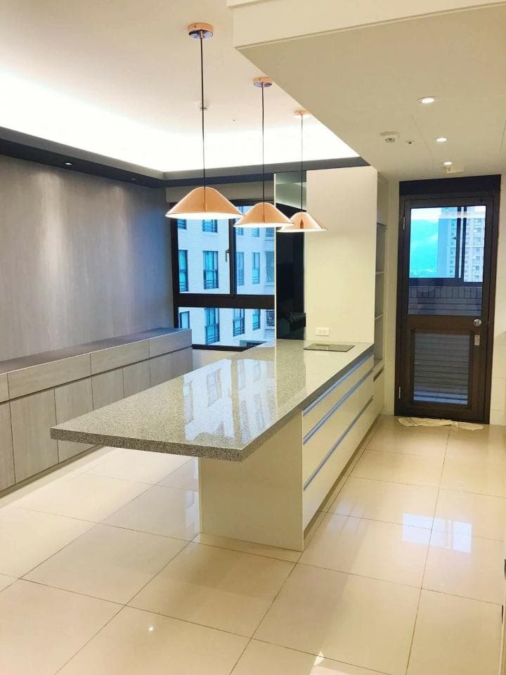 這張照片是時尚的廚房中島,有著大理石檯面和簡潔的設計,搭配三盞玫瑰金吊燈,營造出優雅舒適的氛圍。