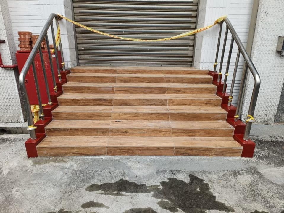 1) 這是一張照片,顯示了一組帶有扶手的木質樓梯,樓梯上有一個黃色的警戒線