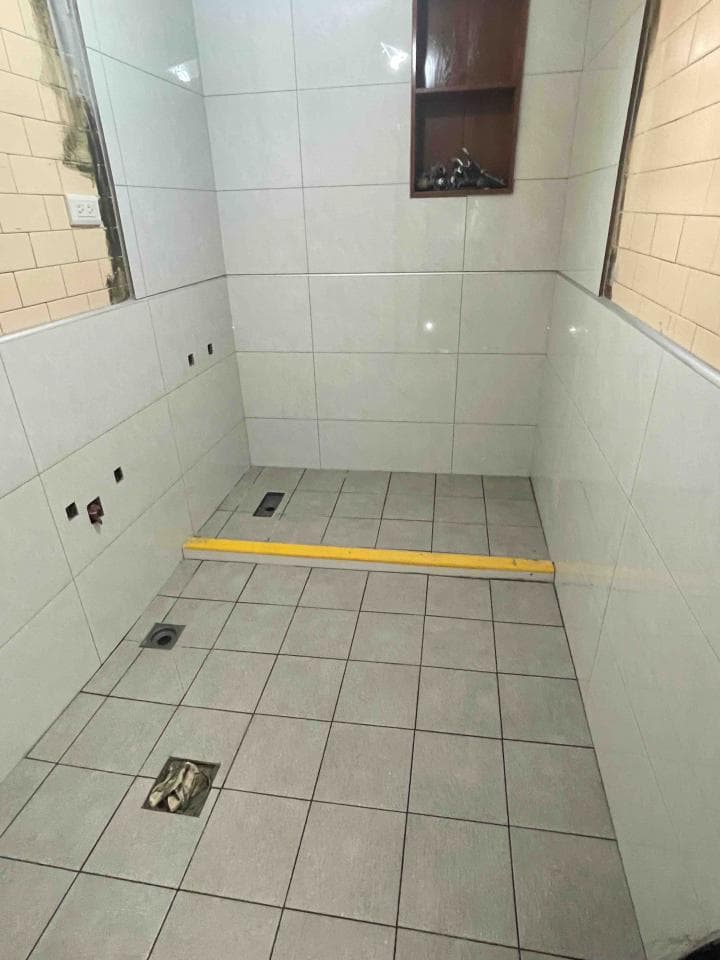 1) 照片顯示一個裝修完成的浴室,牆壁和地板都鋪設了瓷磚,地板上有黃色的條狀磁磚