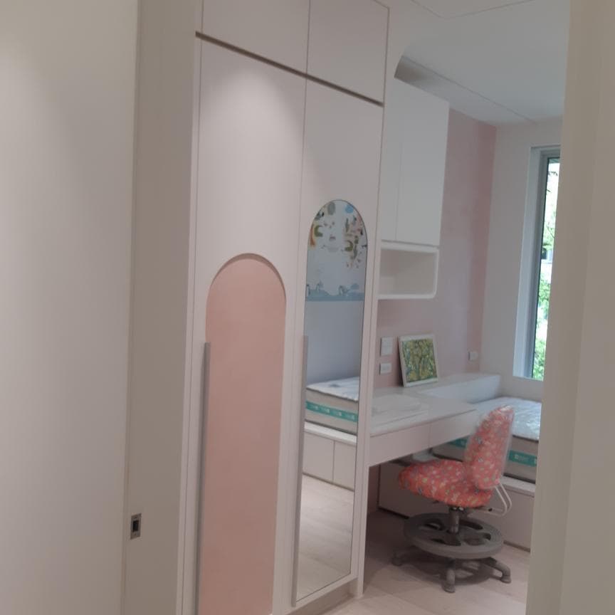這張照片是一個女孩的房間,最重要的是房間的衣櫃。衣櫃是白色的,上面有一個拱形的粉色面板,讓整個衣櫃看起來更加時尚和可愛。