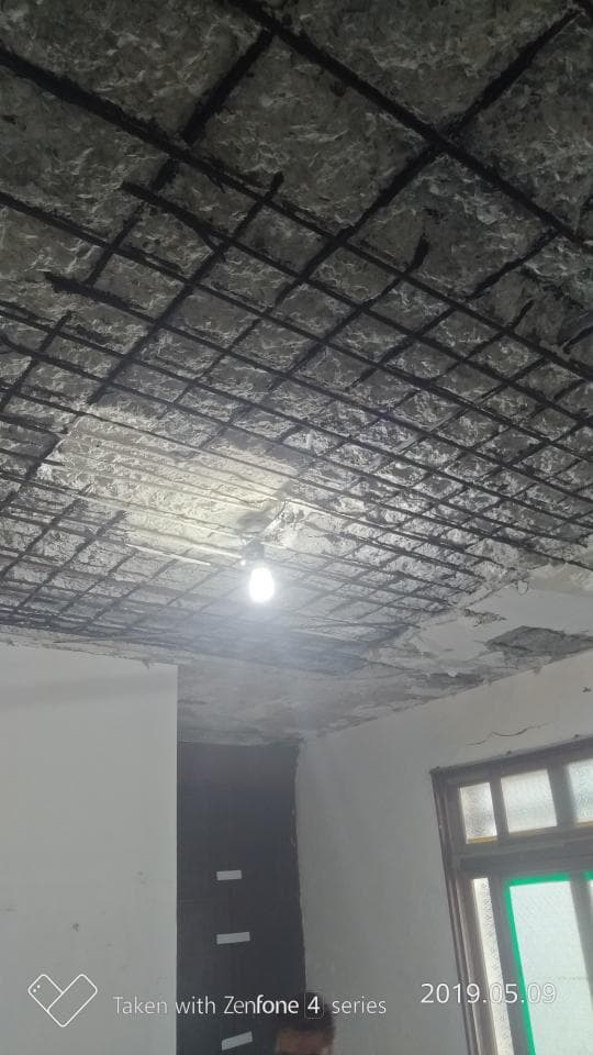 這張照片是一個有破損的天花板,天花板上有鋼筋網格,網格上有一些水泥。