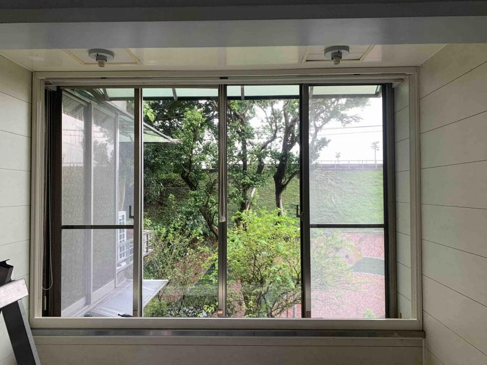 1) 照片顯示一個帶有百葉窗的窗戶,窗戶外是綠樹成蔭的景色