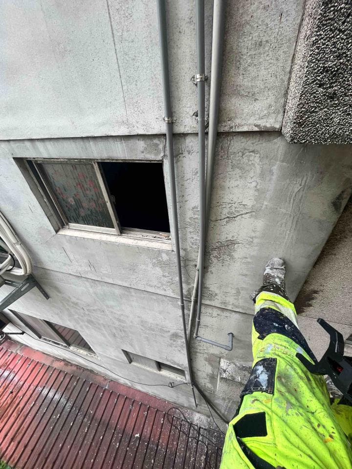 這張照片是一個穿著黃色制服的工人從高處懸掛在建築物外牆。