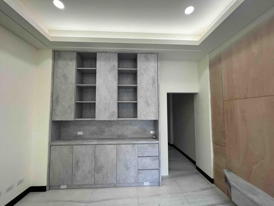 這張照片是一間現代化的臥室,最重要的是牆上的水泥色置物櫃,櫃子分為上下兩層,上層是開放式的層架,下層是封閉式的櫃子,可以放置許多物品,讓臥室更整潔。