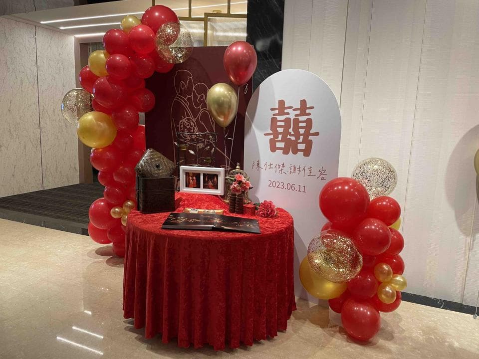 這張照片是一對新人婚禮的佈置,最重要的是印有「囍」字的紅色牌子,上面寫著結婚日期和祝福語。