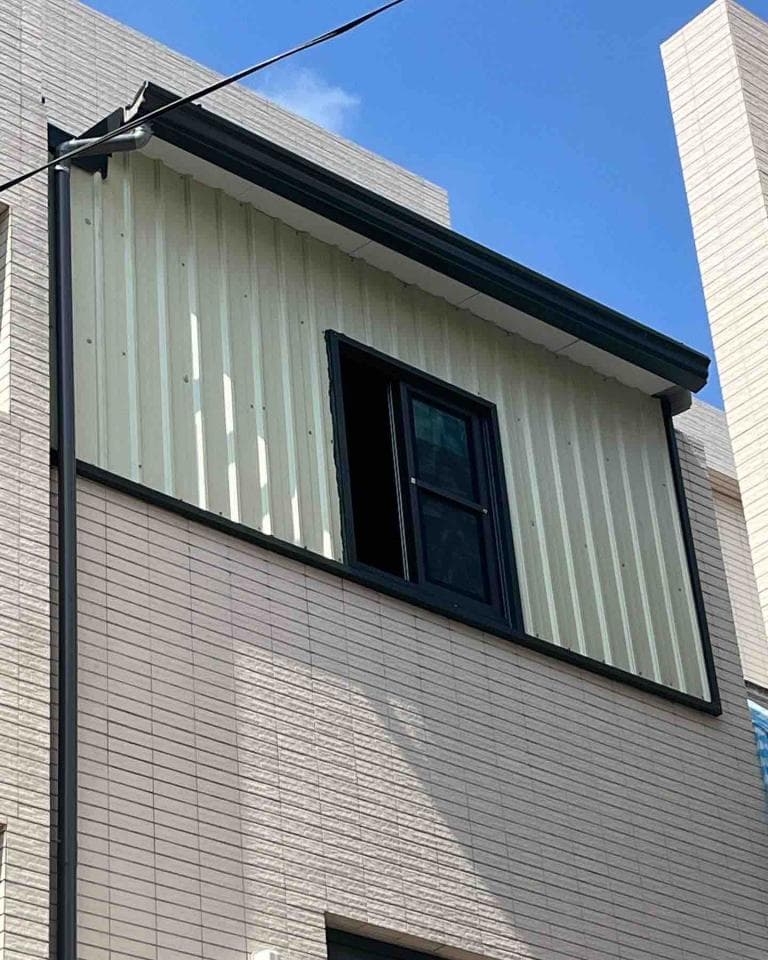 1) 照片顯示一棟建築物的外牆,牆上有一扇窗戶,窗戶是黑色的,牆壁是白色的