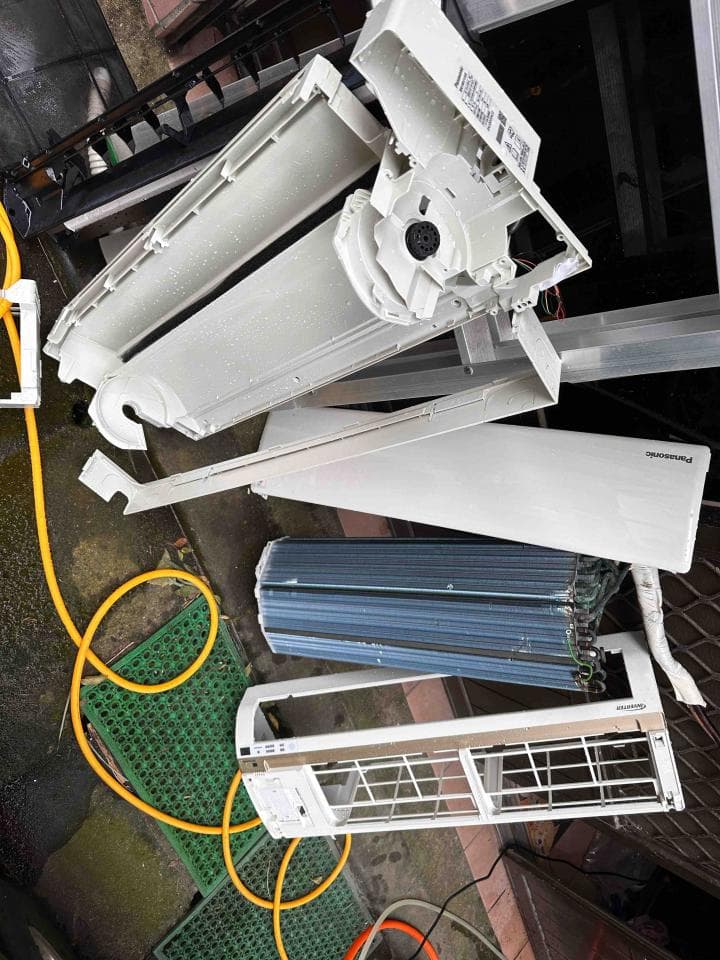 1) 照片顯示拆卸的空調機,包括外殼、風扇、過濾網等零件