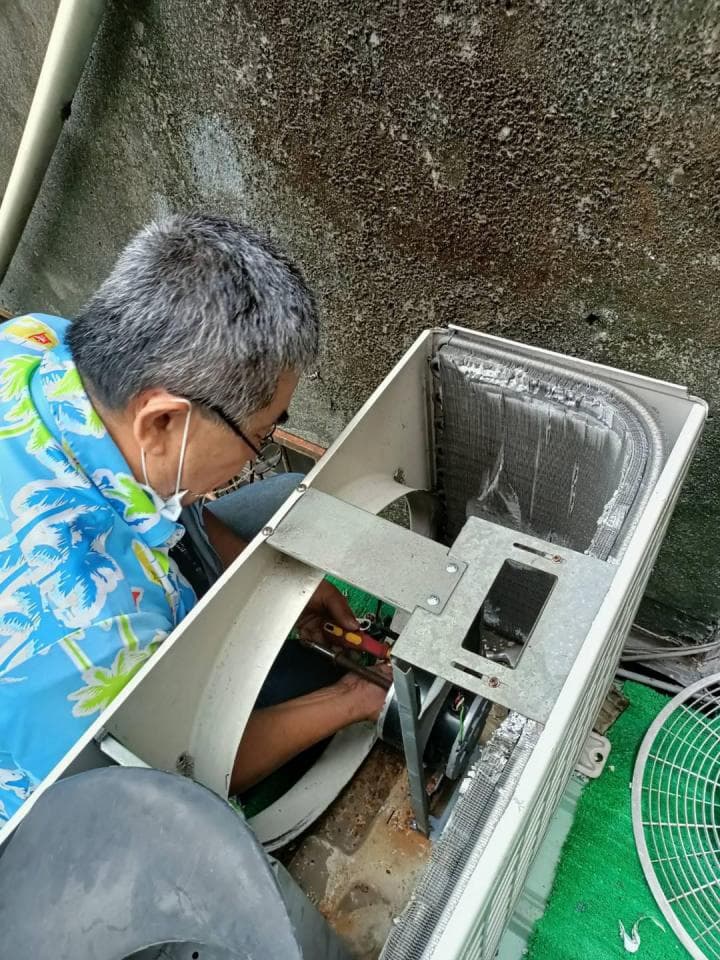 1) 照片中,一名身穿藍色花襯衫的男子正修理一台空調的風扇