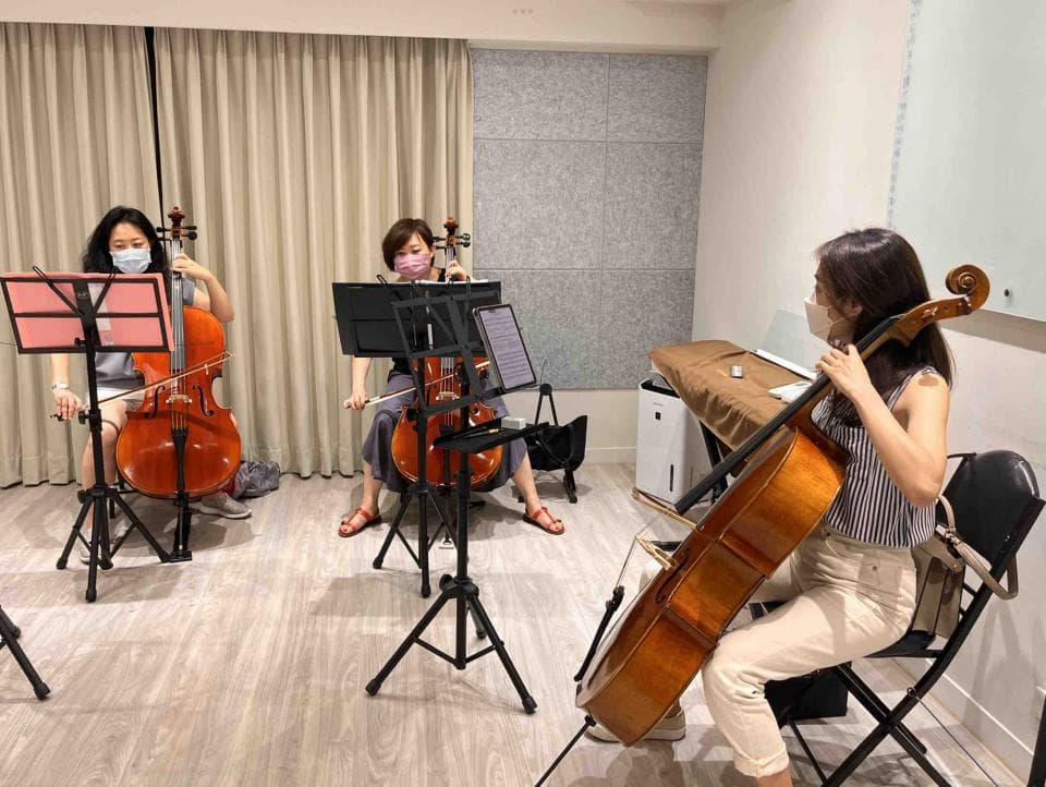 1) 照片中,三位女性坐在房間裡,演奏大提琴