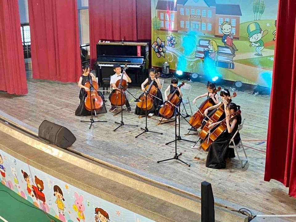 1) 照片顯示一群年輕女孩在舞台上演奏大提琴