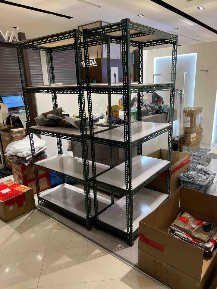 這張照片是兩排金屬架,上面放著一些物品,架子旁邊有一個大的紙箱。