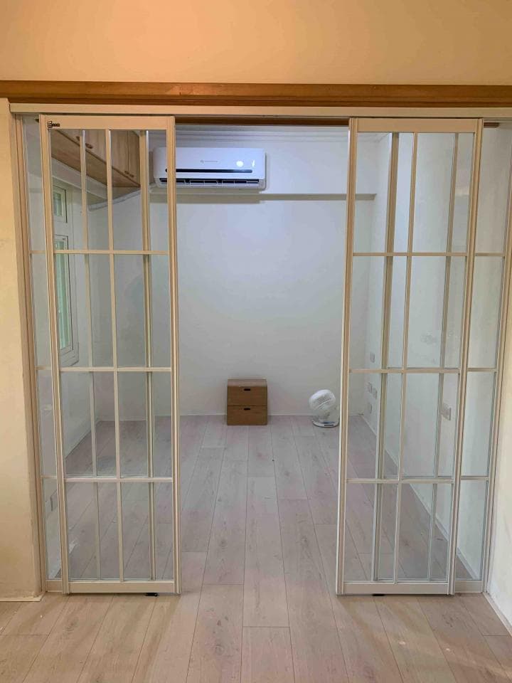 這張照片是一間房間裡面的兩扇玻璃推拉門。門是用白色框架和透明玻璃製作的,設計簡潔,看起來很現代,而且非常明亮。