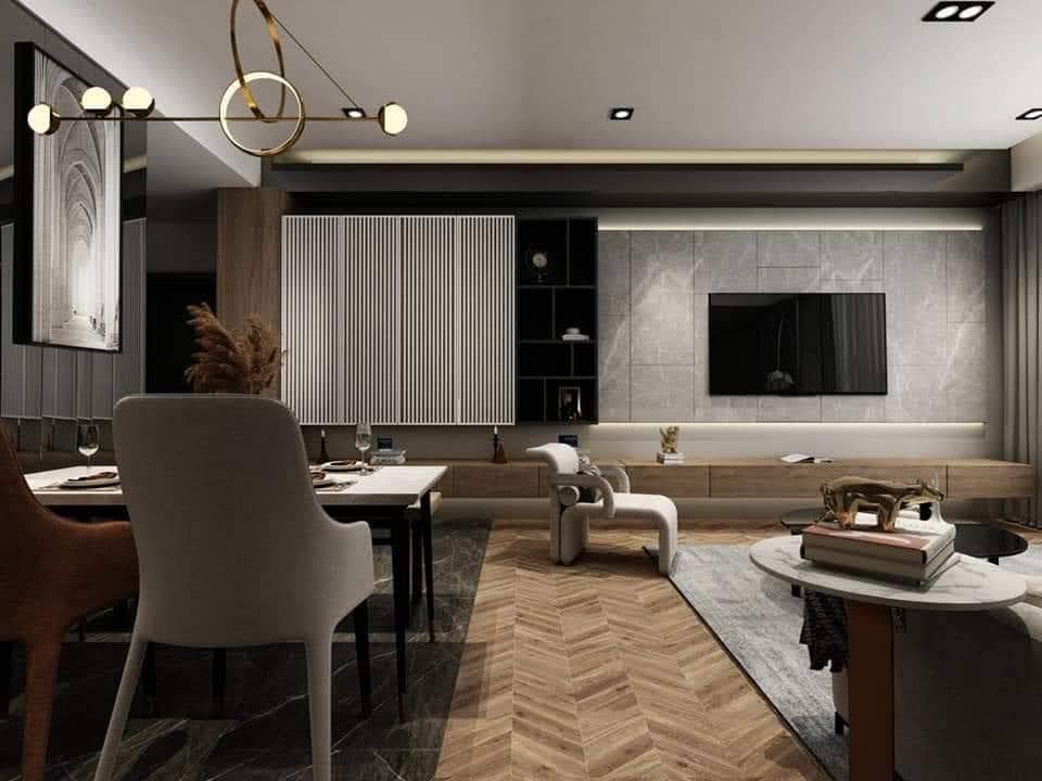 這張照片是現代化的客廳,重點是牆上的電視。電視下方是木質的電視櫃,電視櫃上放著一些裝飾品。電視背景牆採用了灰色石材,營造出簡潔大方的氛圍。