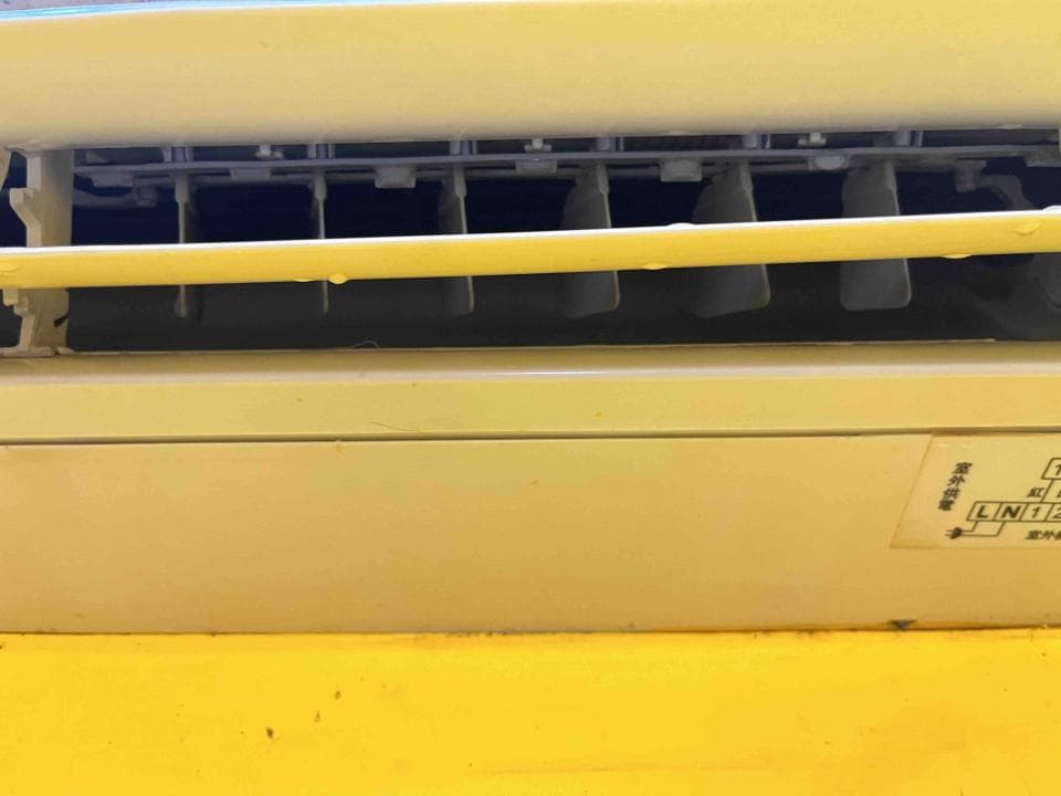 1) 照片顯示一個黃色和白色的空調,其格柵狀進氣口在圖片的上半部分可見