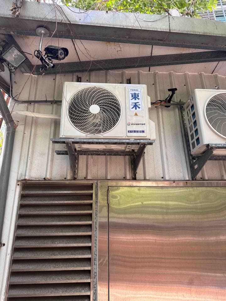 1) 照片顯示一棟建築物的外部,有兩個窗式空調,一個裝在另一個的上面