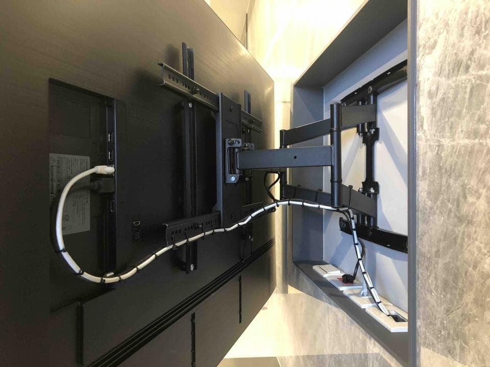 1) 照片顯示一個黑色電視螢幕安裝在牆上的支架上