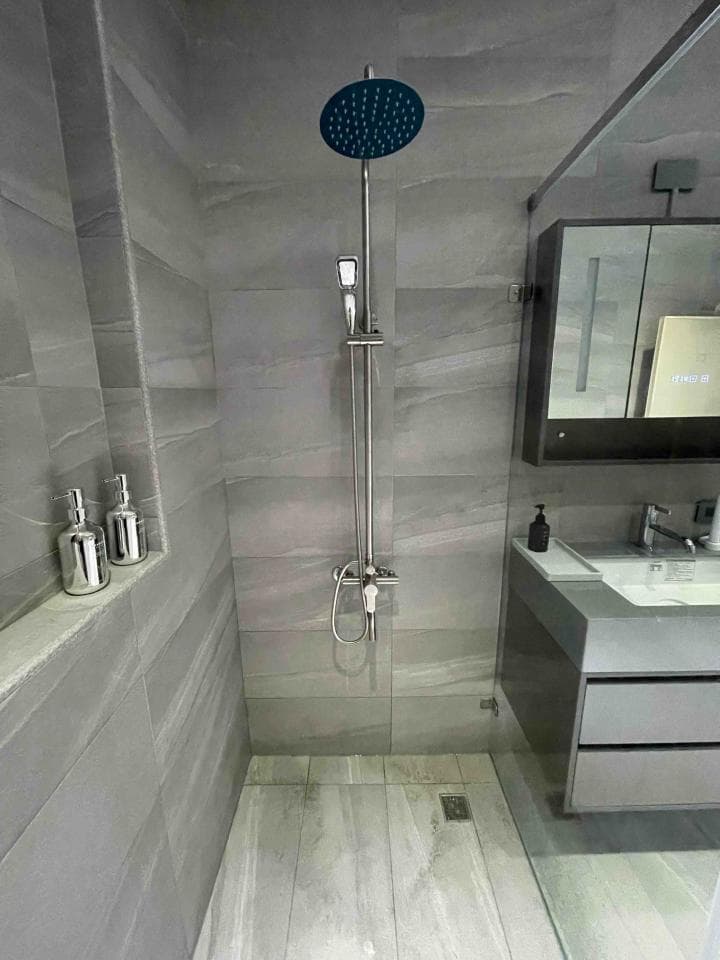 1) 照片顯示一個帶有淋浴頭和牆上瓷磚的淋浴間