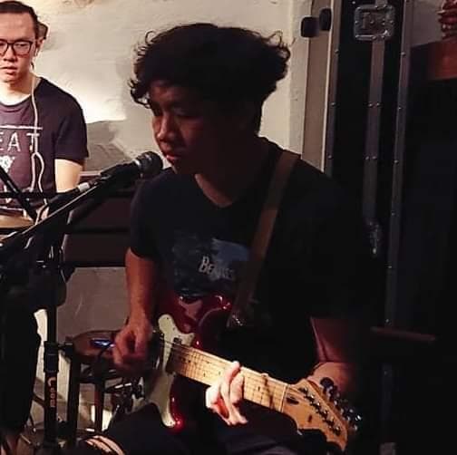 這張照片是一個年輕人在彈奏電吉他。他專注地看着吉他,手指靈活地在琴弦上跳動,演奏出美妙的音樂。