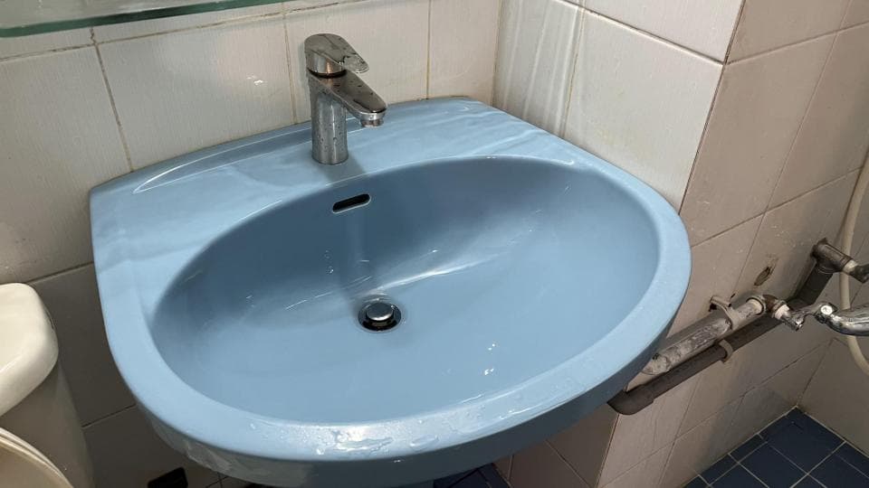 這張照片是一間浴室的洗臉盆。洗臉盆是淺藍色的,有一個銀色的水龍頭,水龍頭上有一個小圓形的把手。