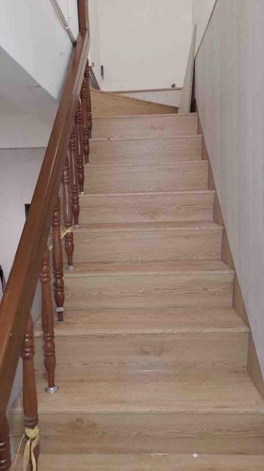 這張照片是一段木質樓梯,樓梯扶手是深色的木頭,樓梯的踏板是淺色木紋。