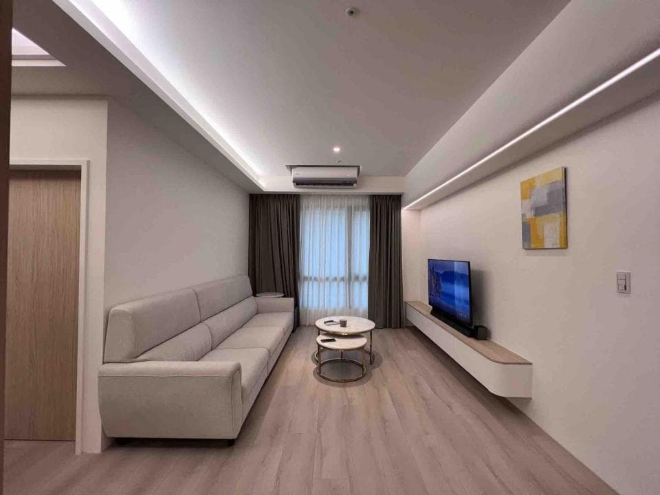 這張照片是一間現代化的客廳,最顯眼的是牆上的懸掛式電視櫃,它結合了簡約的設計,和白色牆壁形成鮮明的對比,突顯了電視的存在。