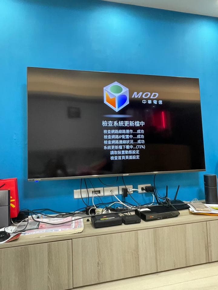 1) 照片顯示一台掛在牆上的液晶電視,電視畫面顯示的是一個正在更新的系統介面