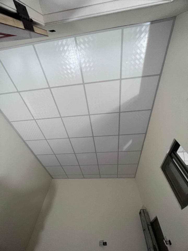 這張照片是一個房間的天花板,由許多白色正方形的格狀天花板組成。