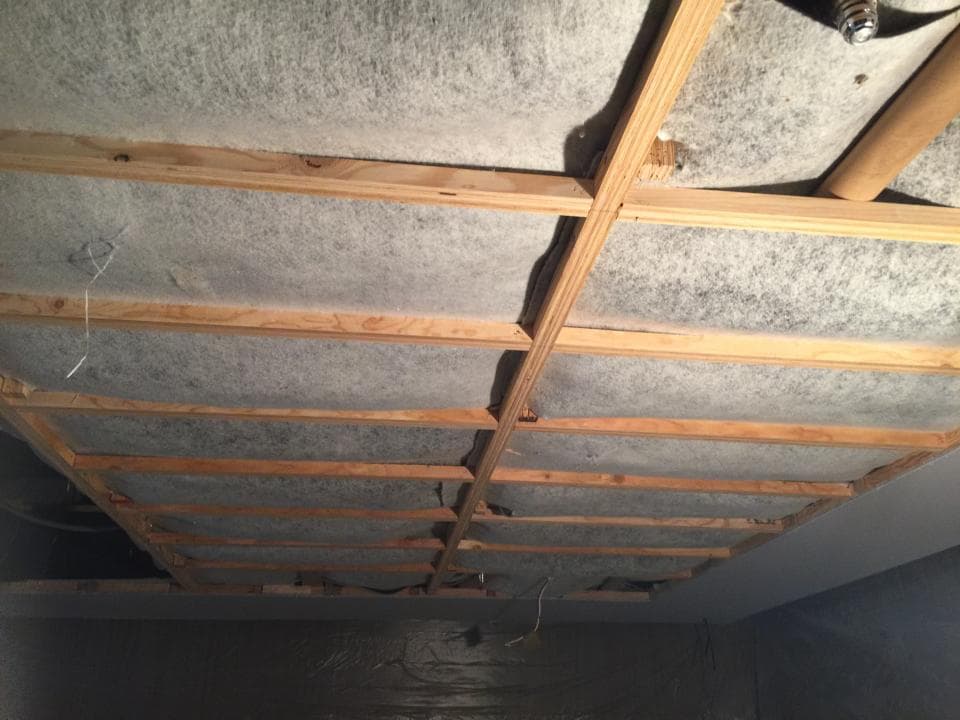 1) 照片顯示一個木製天花板,天花板由多個木條組成,木條之間填充了灰色的隔熱材料