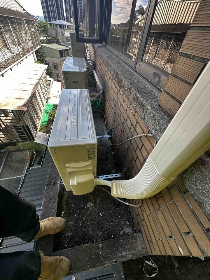 1) 照片顯示一個建築物的外牆,牆上裝有兩個冷氣室外機和一個白色的排氣管