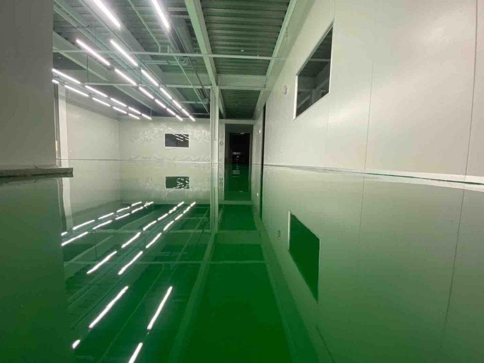 1) 照片顯示一個有著綠色地板的長廊,地板反射著天花板上的燈光,走廊的牆壁是白色的