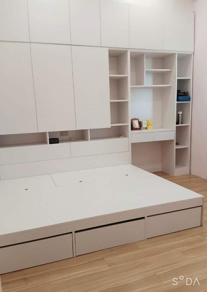 1) 照片顯示一個白色床架,床架上有一個白色床墊,床頭板上有幾個白色櫃子,左邊是衣櫃,右邊是書櫃,地板是木地板