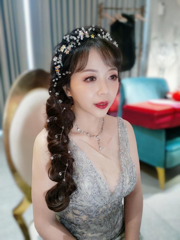 這張「婚禮」的照片是一個穿著蕾絲禮服的女性,她戴著精緻的花朵頭飾,正在整理頭髮。