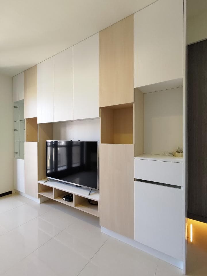 1) 照片顯示一個現代化的客廳,裡面有一面牆的白色和木色櫃子,中央有一個平板電視