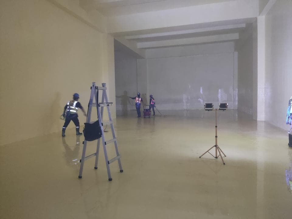 1) 照片顯示一個大型空置空間,裡面有一個人正在使用梯子工作,還有一個三腳架和燈光設備